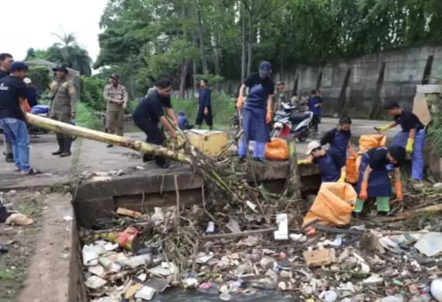 Petugas sedang membersihkan sampah di genangan air