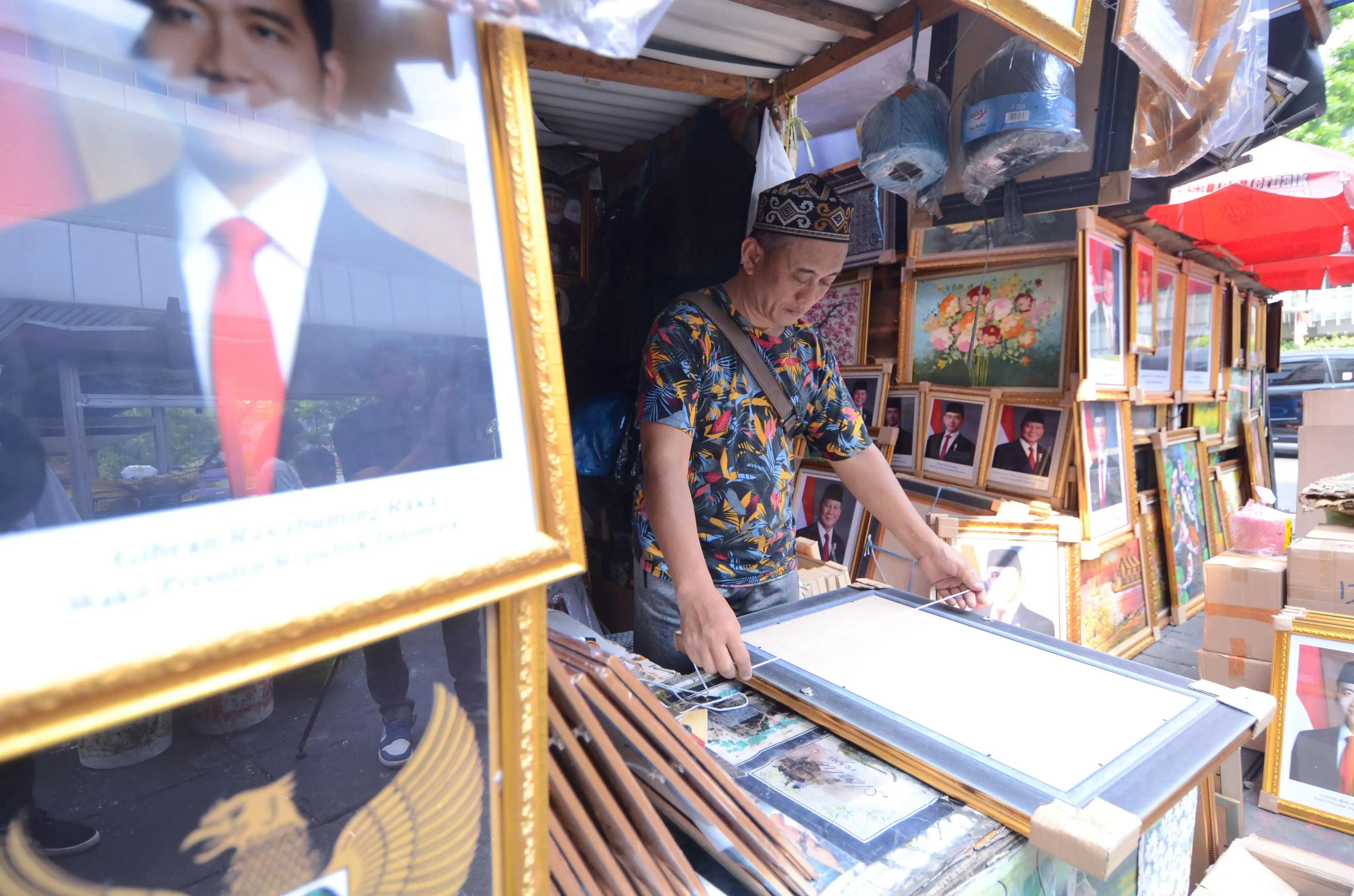 Pedagang mengukur bingkai foto presiden Prabowo Subianto (Foto: Dok MI/Donavita)