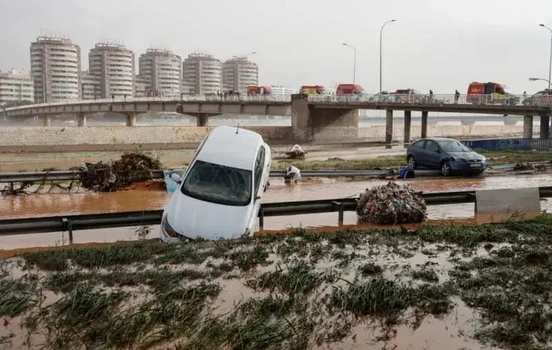 Sebuah mobil tersangkut di atas pembatas jalan sementara di latar belakang (Foto: Getty Images)