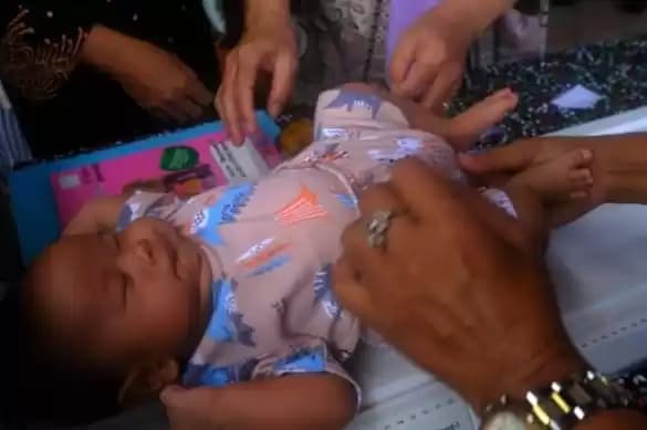Foto Kader posyandu mengukur tinggi badan bayi