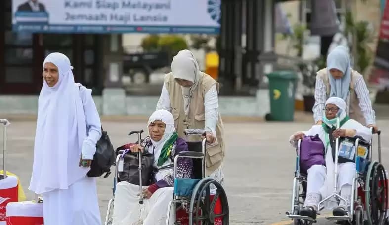 Foto Petugas mendorong kursi roda calon haji lansia menuju aula