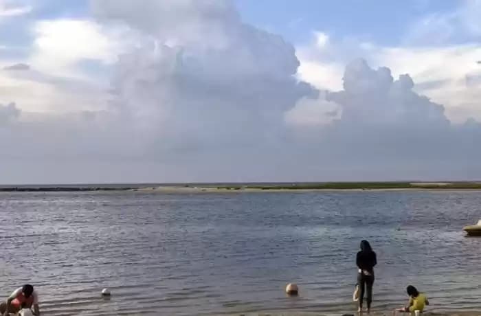 Ilustrasi - Wisatawan bermain di tepi pantai saat cuaca cerah berawan di wilayah Jakarta