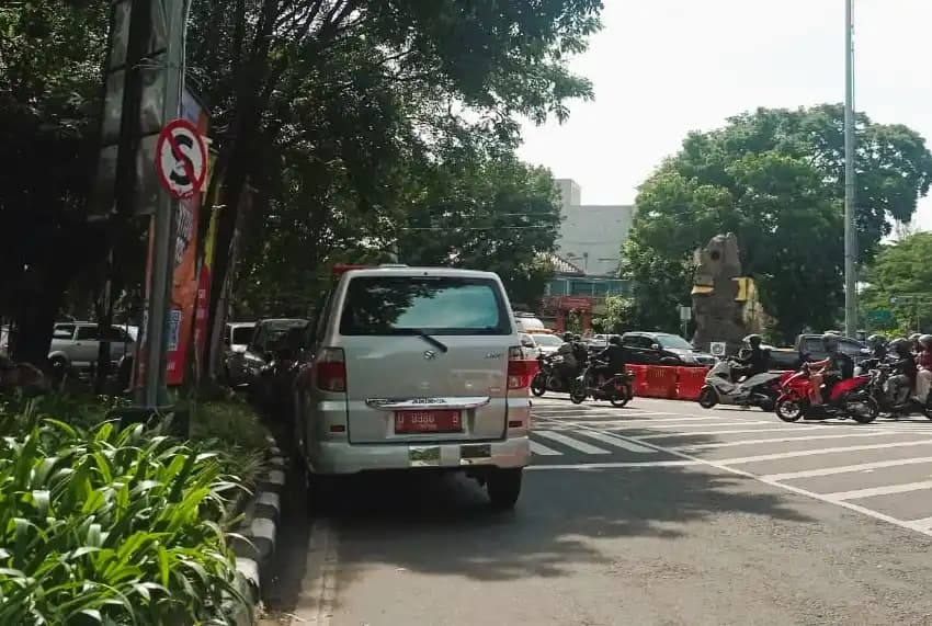 Kendaraan plat merah yang parkir sembarangan di bahu jalan depan kantor Dinkes Kota Bandung, Jawa Barat