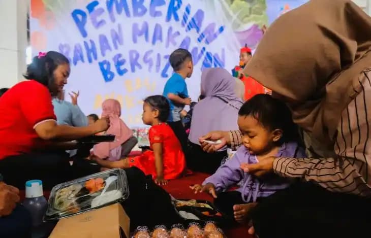 Para ibu dan anak mereka menghadiri acara Pemberian Bahan Makanan Bergizi