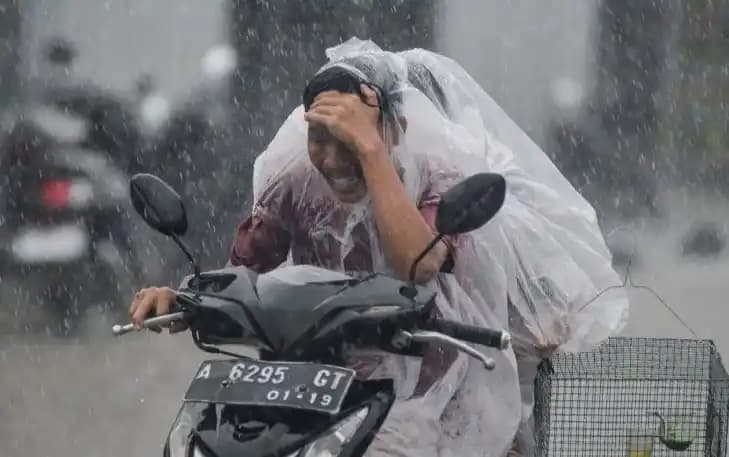 Pengendara motor mengenakan jas hujan