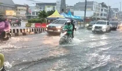 Pengendara sepeda motor dan roda empat terlihat melintasi jalanan banjir