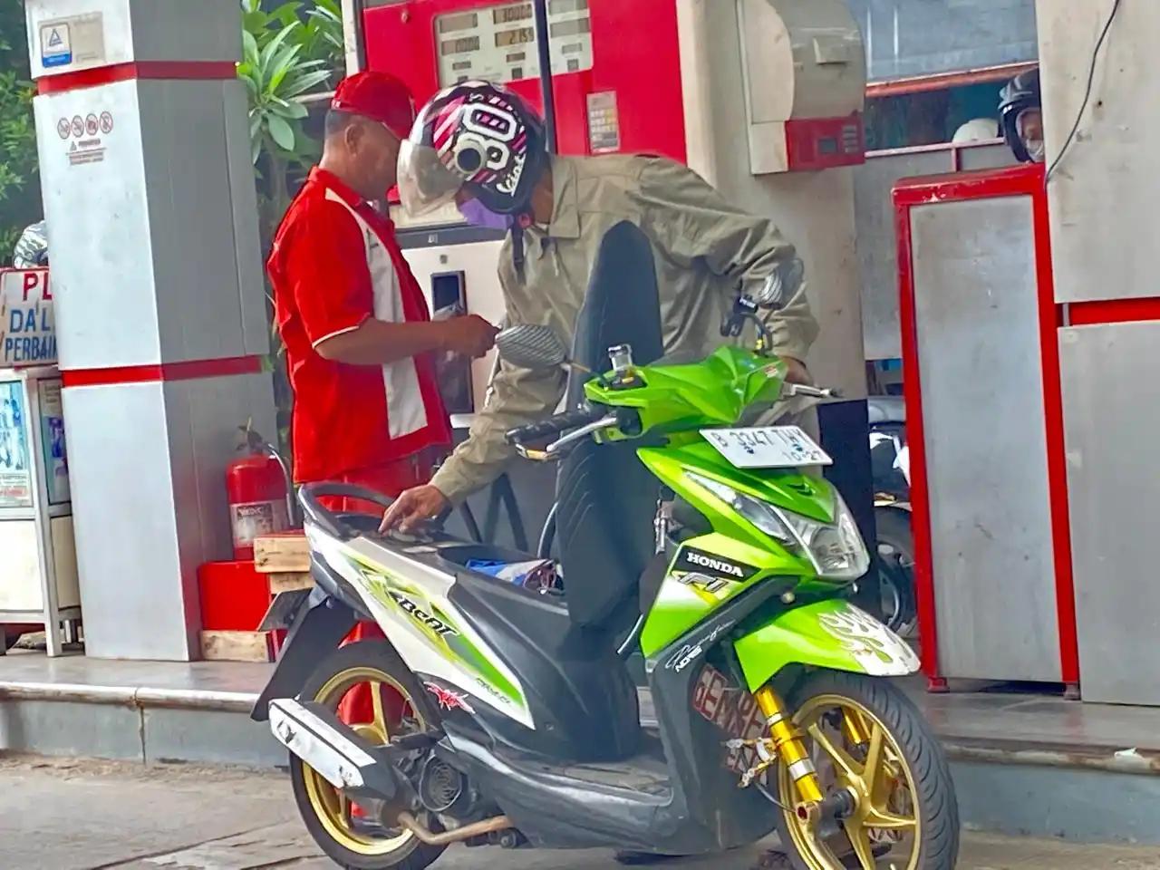 Pengendara sepeda motor sedang mengisi BBM