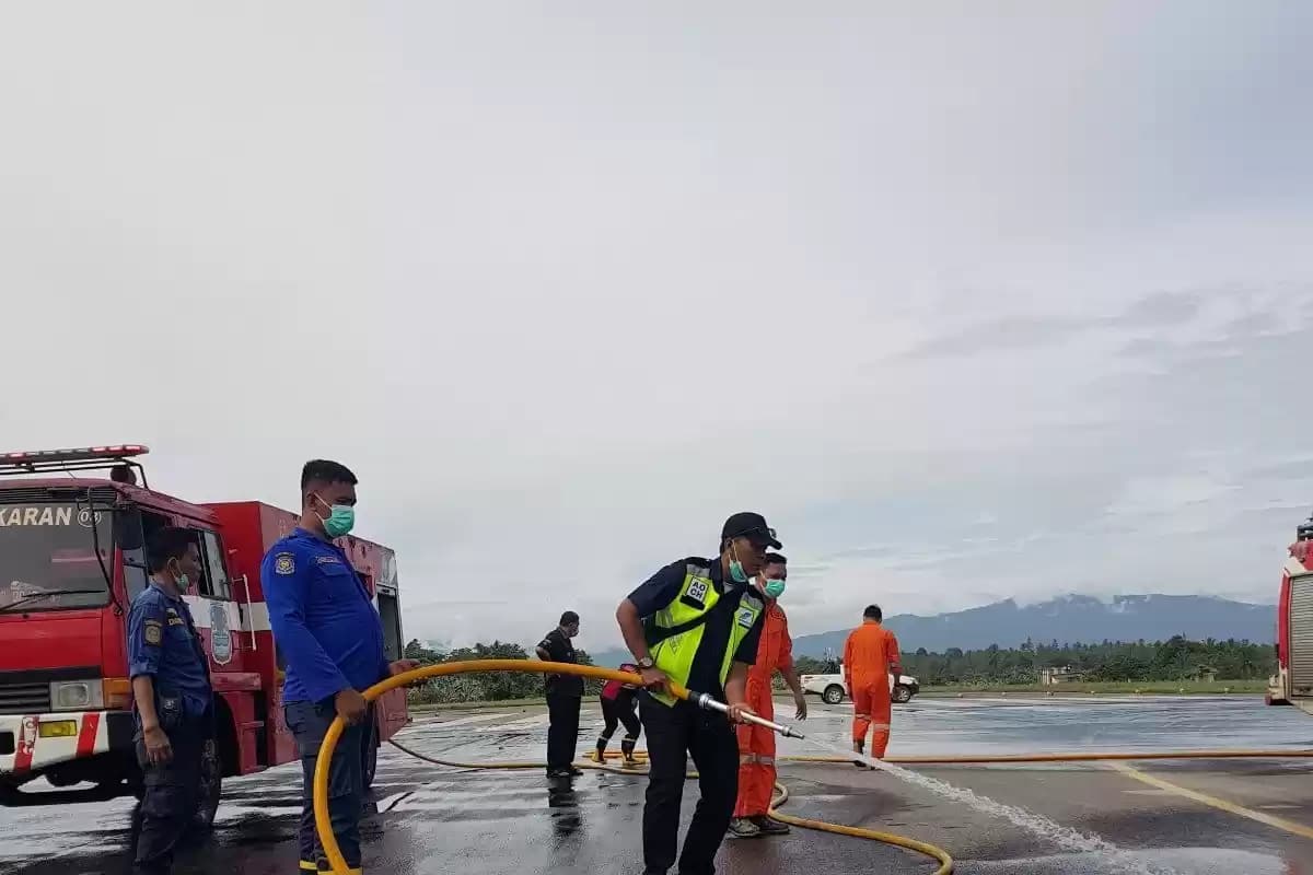 Petugas saat membersihkan landasan Bandara Samrat dari abu vulkanik, di Manado, Rabu (1/5/2024). (Foto: ANTARA)