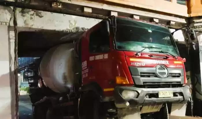 Sebuah truk molen bernomor polisi B 9475 SIN tersangkut di kolong jembatan perlintasan rel kereta