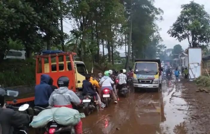 Sejumlah kendaraan melintasi jalan berlumpur bekas banjir di wilayah Cisurupan