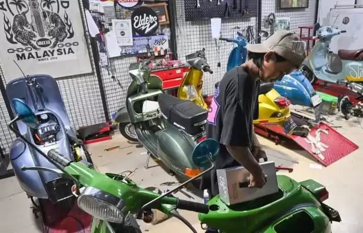 Teknisi mengkonversi sepeda motor berbahan bakar minyak menjadi sepeda motor listrik